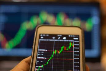 Hand holding a phone with price charts