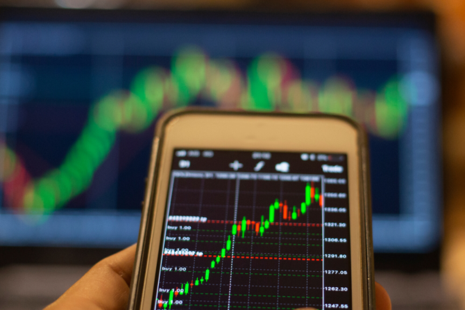 Hand holding a phone with price charts